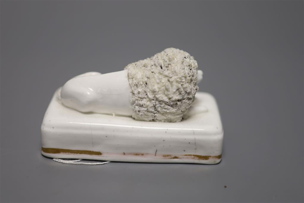 A Staffordshire porcelain poodle, recumbent on rectangular cushion base, c.1850, length 10cm